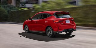 Vista trasera lateral de Chevrolet Aveo HB 2025, nuevo auto compacto con spoiler con luz de freno y antena de tiburón